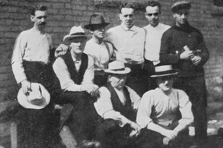 A group of eight men pose for a photo.