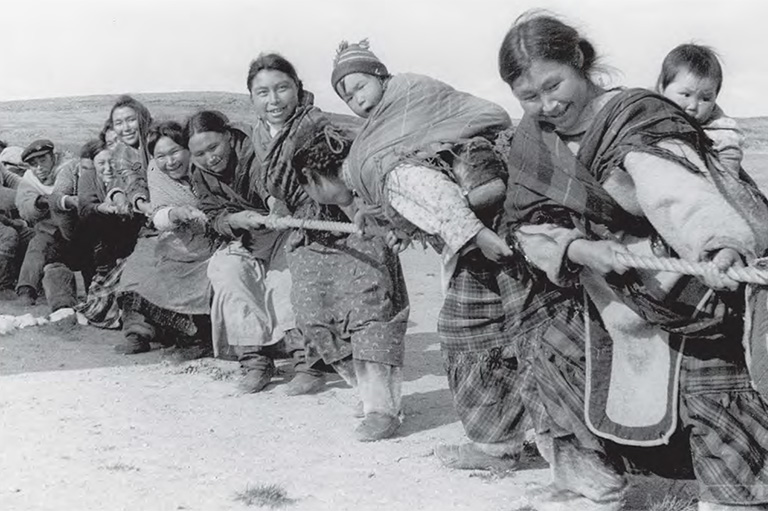 Un groupe de personnes sourit et tient une corde lors d'un jeu de souque-à-la-corde.