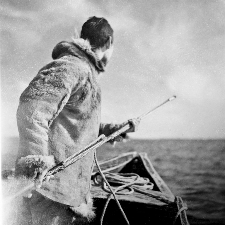 Un homme en parka tient un harpon.