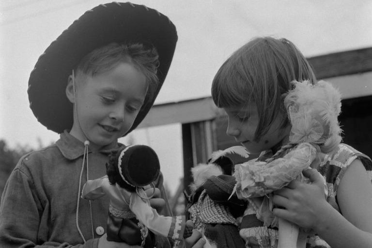 Photo en noir et blan montrant deux enfants et des poupées