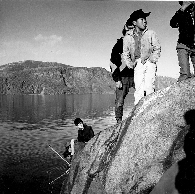 157 / 5000 Translation results Trois garçons se tiennent au sommet d'une paroi rocheuse près de l'eau. Il y a trois garçons assis plus près de l'eau qui pêchent. La photo est en noir et blanc.