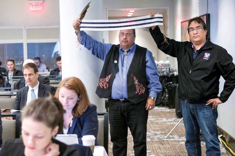 Deux hommes debout avec une ceinture wampum à la main.