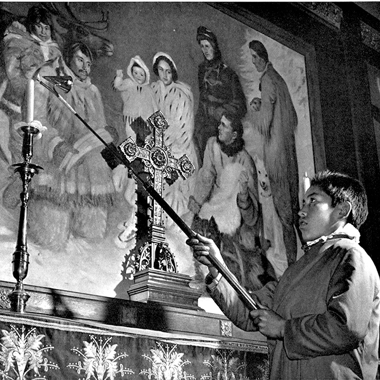 Photo en noir et blanc d'un garçon tenant un grand briquet pour un autel d'église.